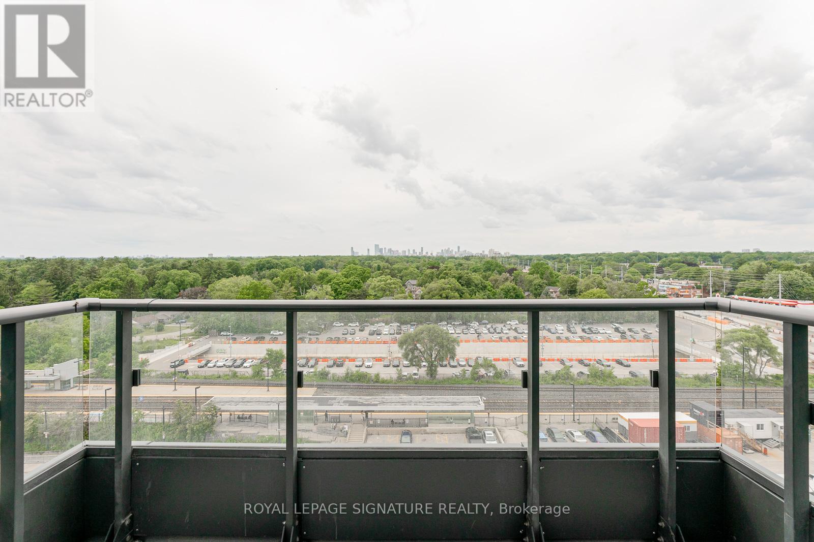 A view from a balcony overlooking a parking lot and buildings.