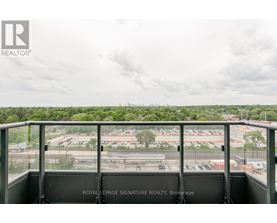 A view from a balcony overlooking a parking lot and buildings.