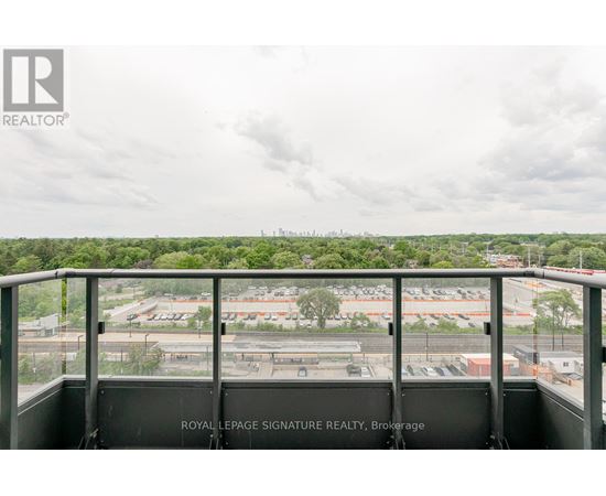 A view from a balcony overlooking a parking lot and buildings.