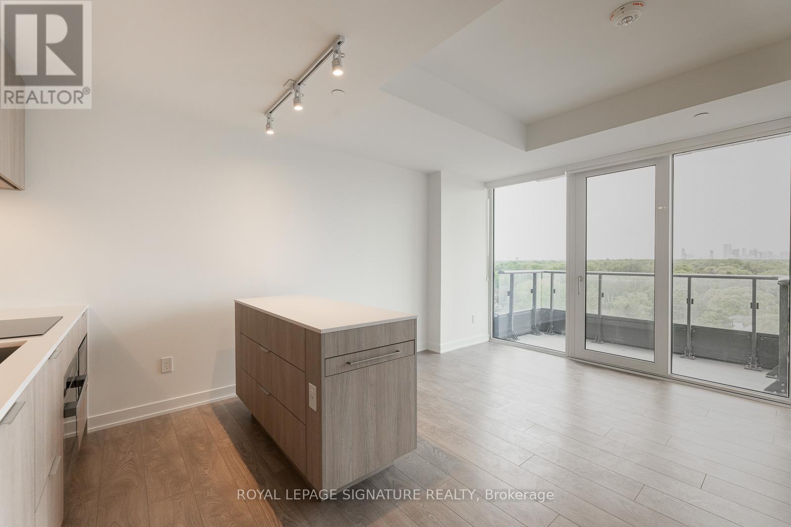 A spacious room with a sliding glass door leading to a balcony.