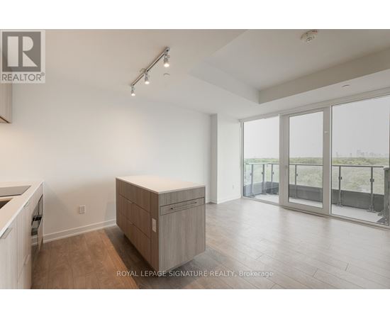 A spacious room with a sliding glass door leading to a balcony.