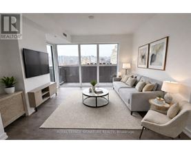 A living room with a flat screen TV, a sofa, a coffee table, and a large window with a view of the city.
