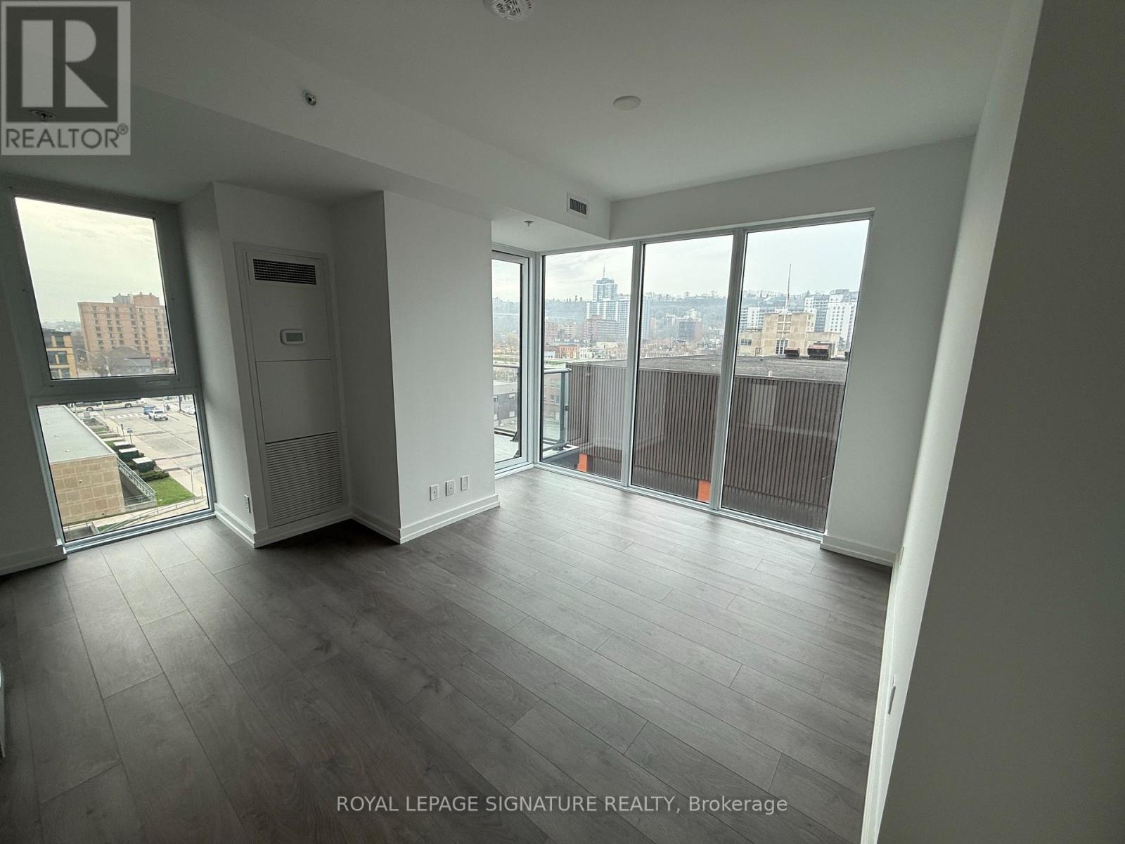 A spacious room with a view of the cityscape through large windows.