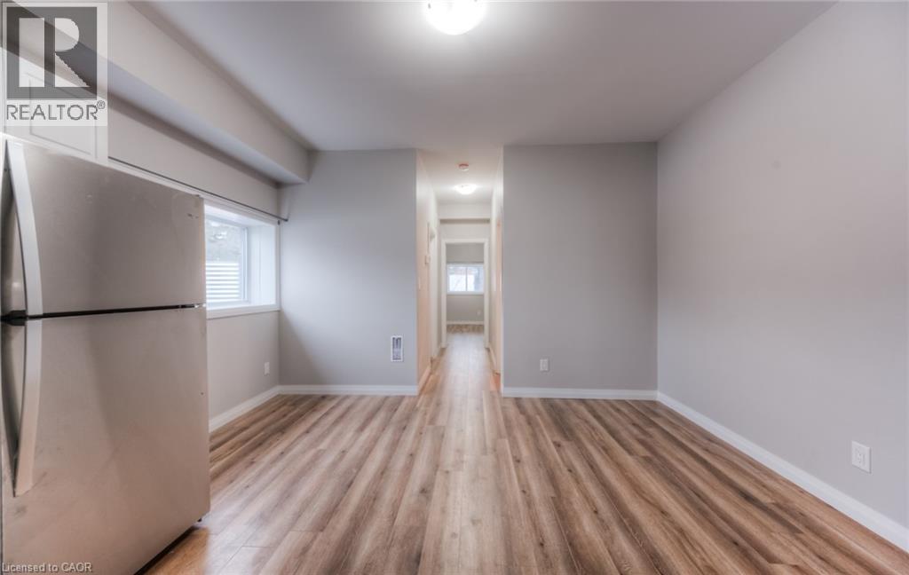 A spacious room with wooden flooring and a refrigerator on the left side.