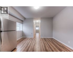 A spacious room with wooden flooring and a refrigerator on the left side.