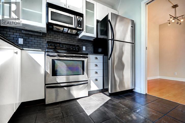 A kitchen with a black fridge and stove top oven.