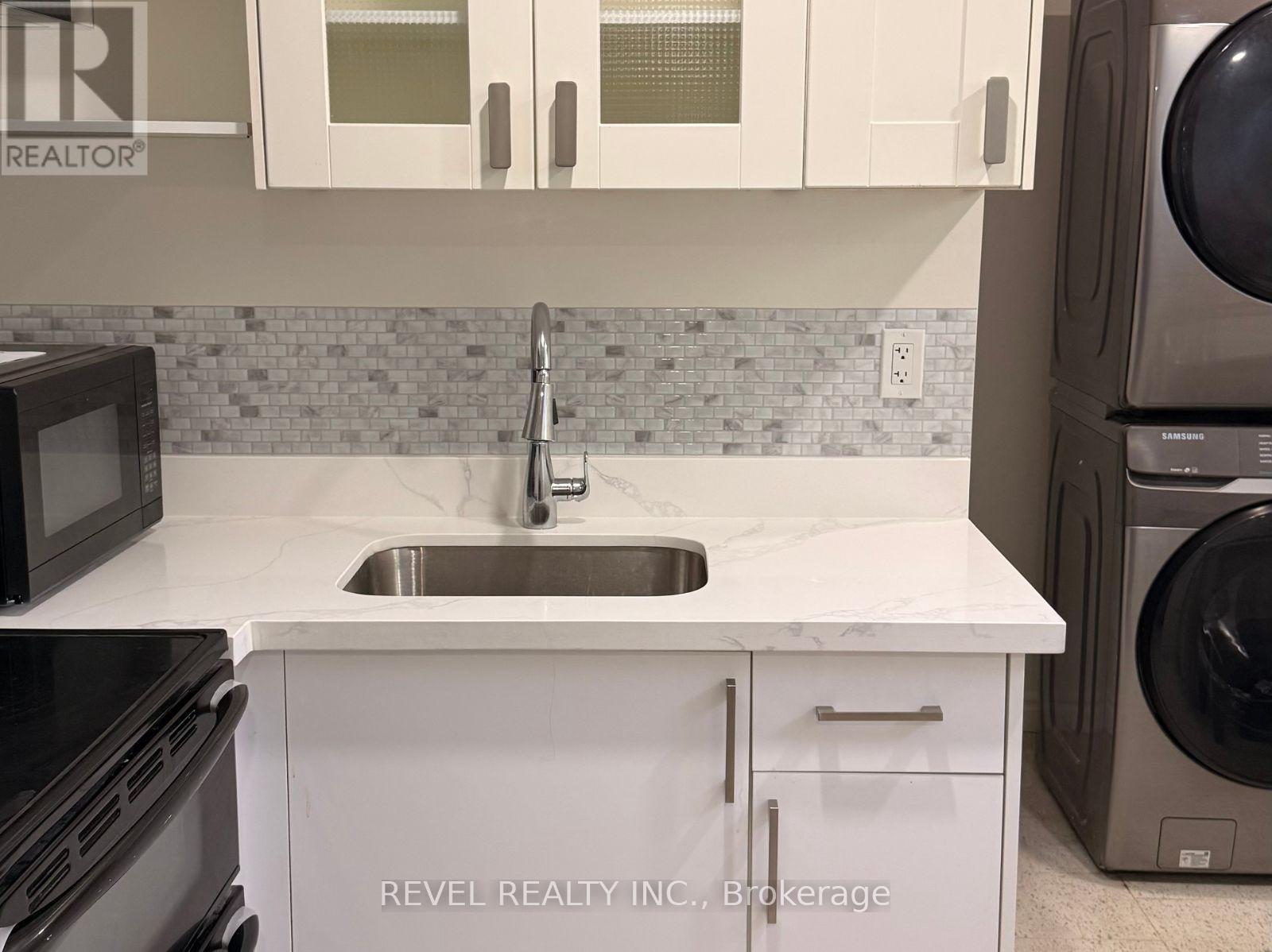 A kitchen with a white counter top and a black microwave.