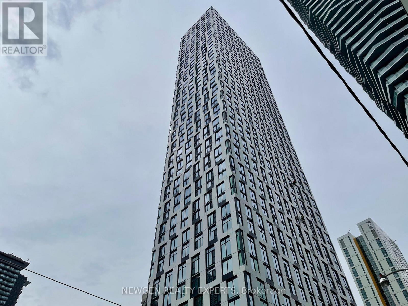 A tall building with many windows is seen from a low angle.