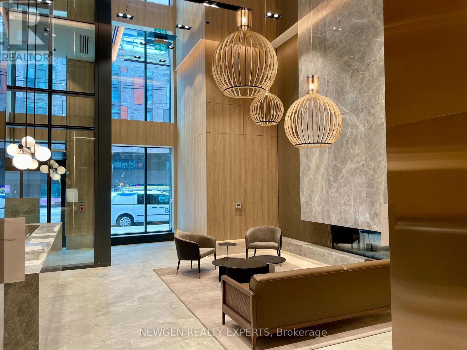 A reception area with a desk, chairs and hanging lights.