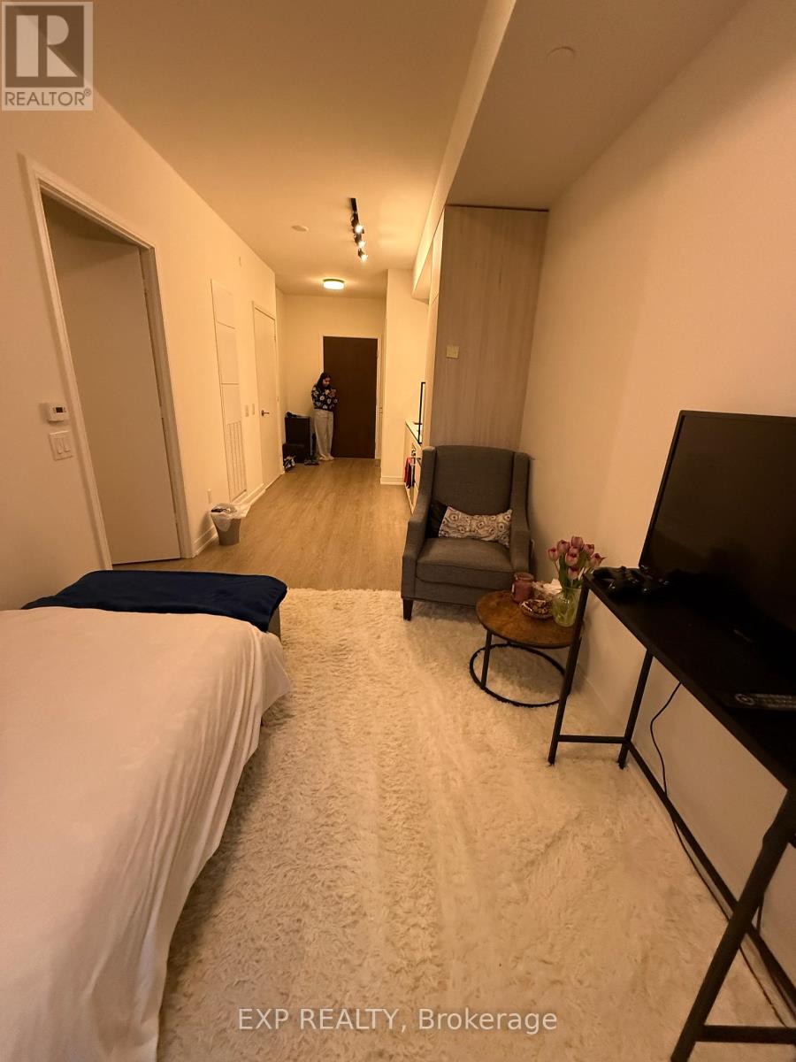 A bedroom with a bed, chair, and television.