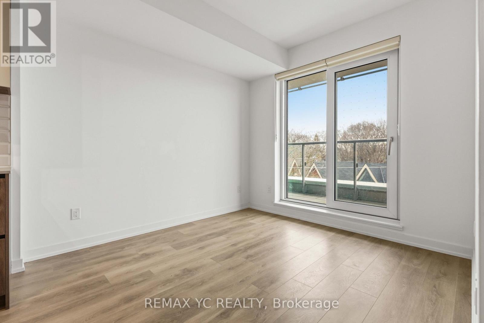 A room with a window showing a view of houses and trees outside.