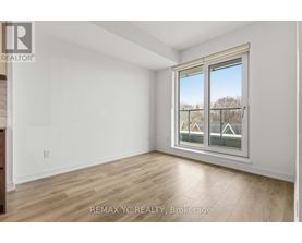 A room with a window showing a view of houses and trees outside.