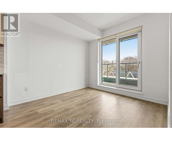 A room with a window showing a view of houses and trees outside.
