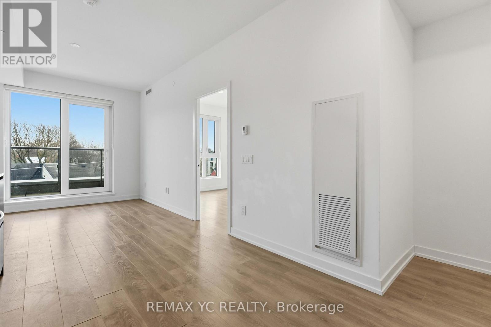 A spacious, empty room with a sliding glass door and a radiator on the wall.