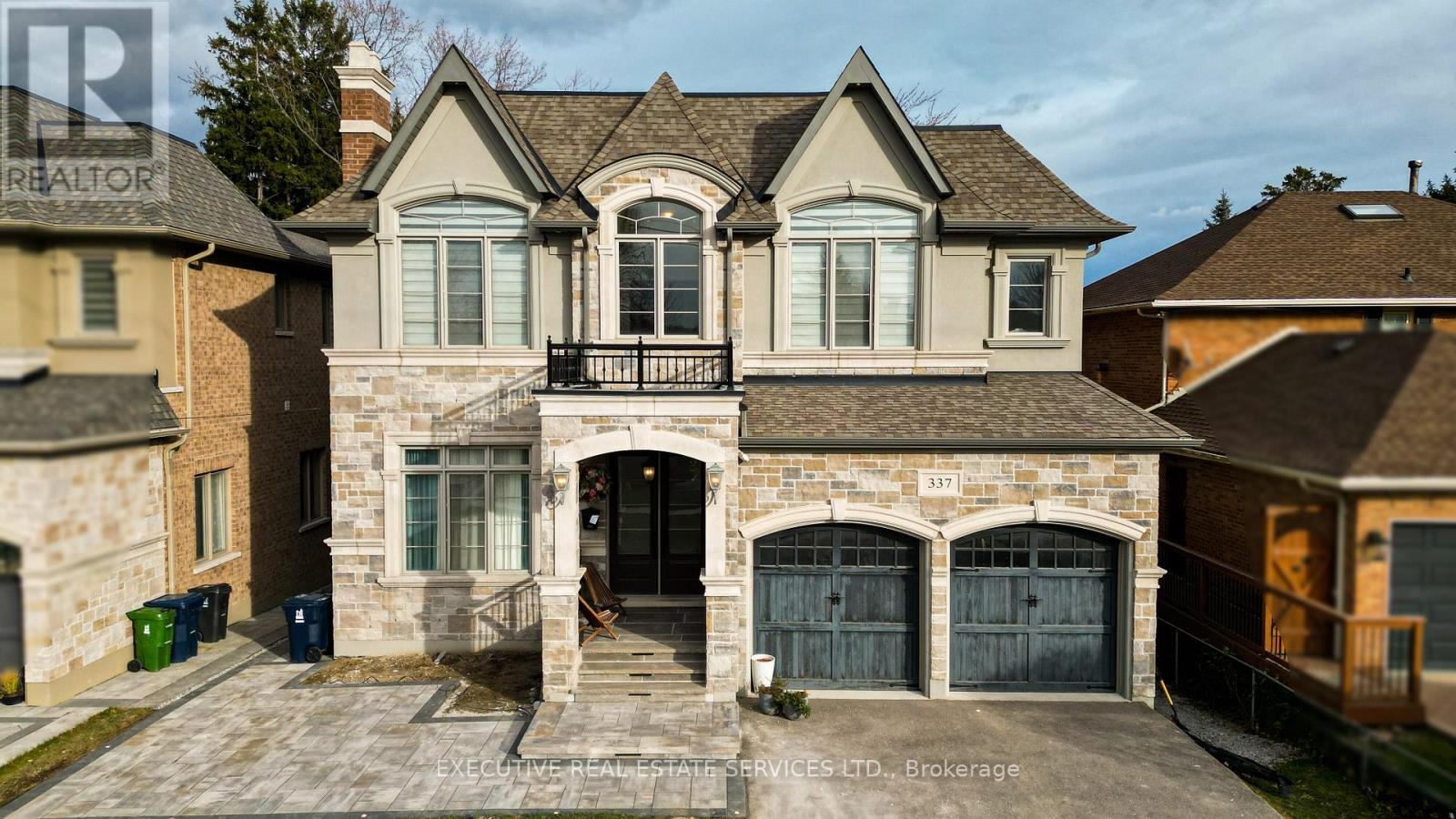 A large house with a stone facade and a black gate.