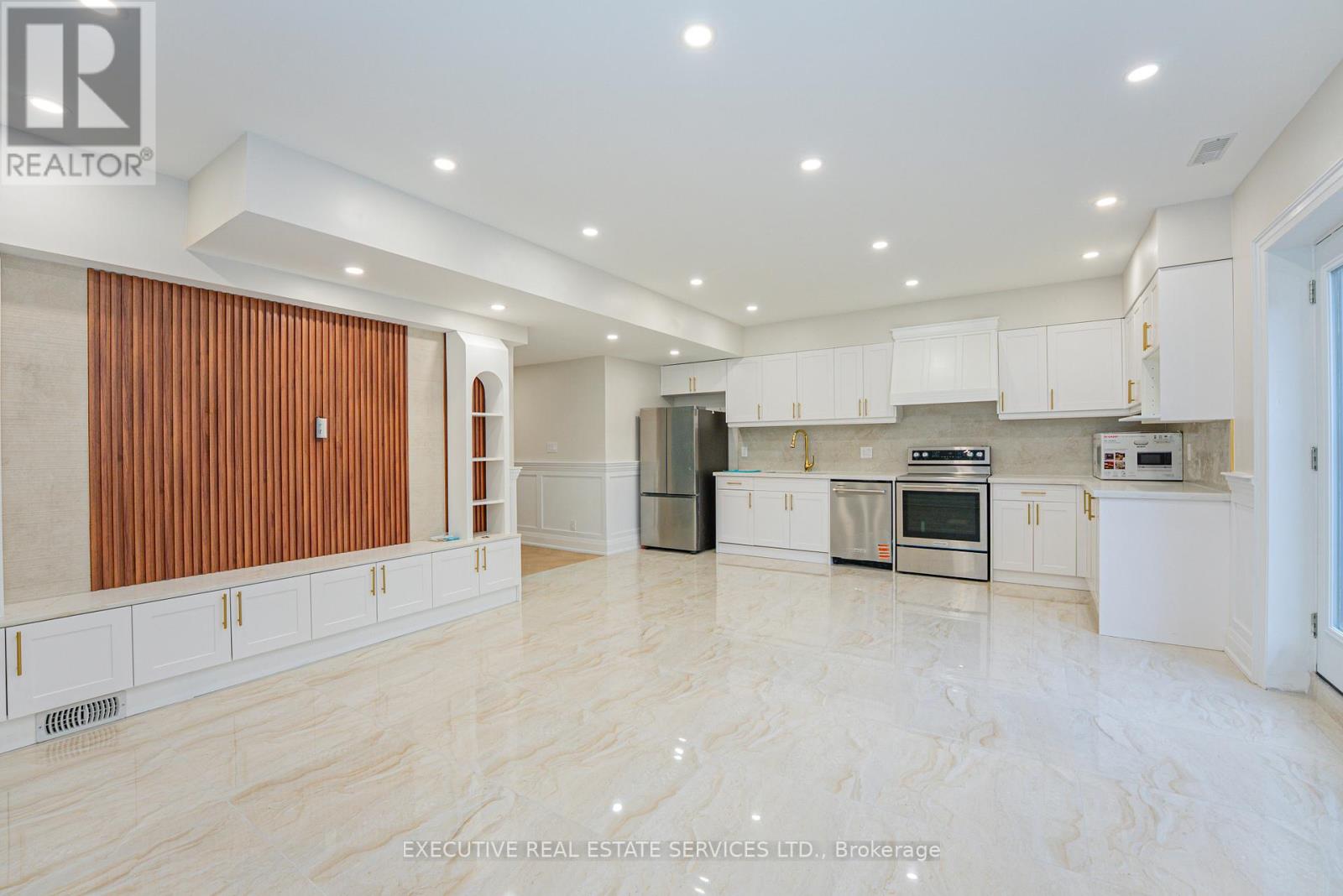 A spacious kitchen with white cabinets and a wooden door.