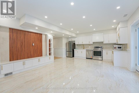 A spacious kitchen with white cabinets and a wooden door.