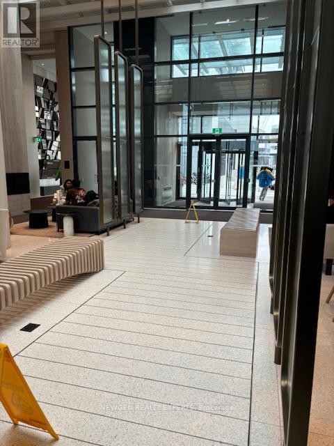 A yellow caution sign is on the floor of a modern building.
