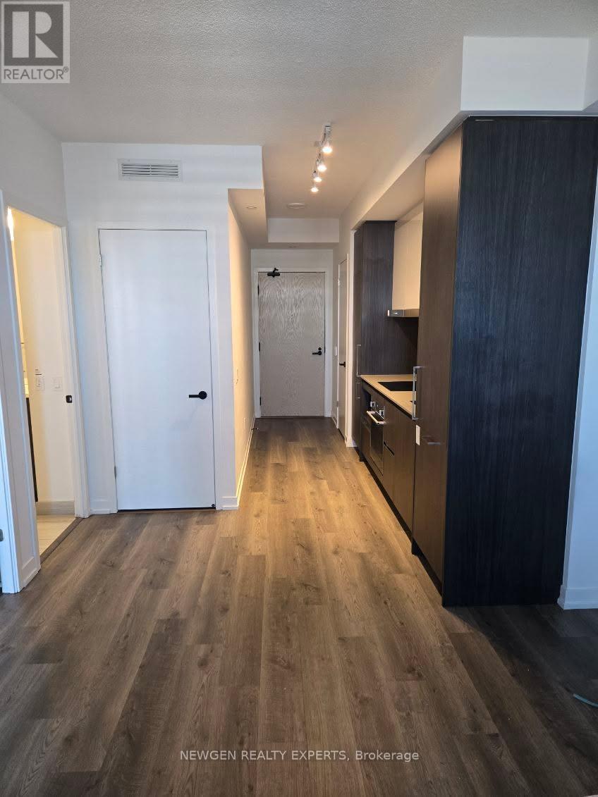 A kitchen with dark wood floors and white walls.