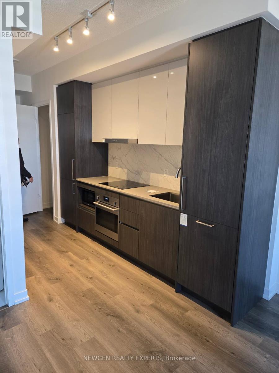 A modern kitchen with dark wood cabinets and a marble backsplash.