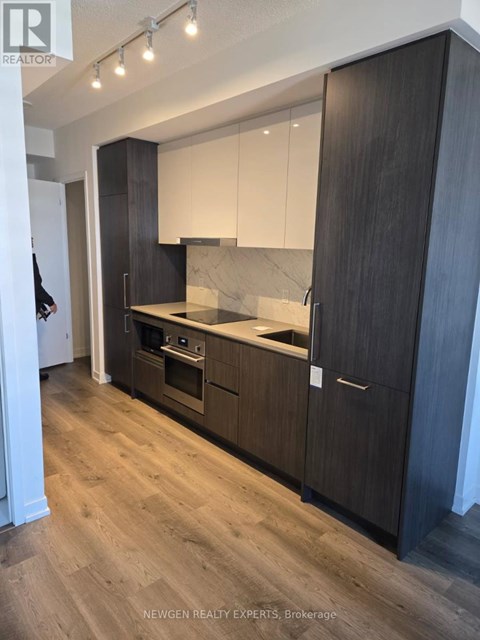 A modern kitchen with dark wood cabinets and a marble backsplash.