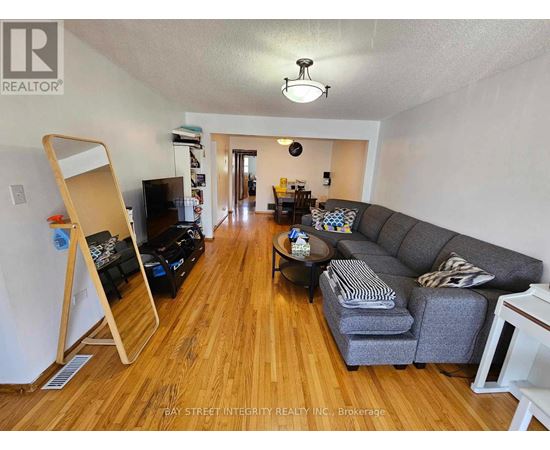 A living room with a grey couch and wooden floors.