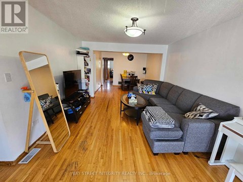 A living room with a grey couch and wooden floors.