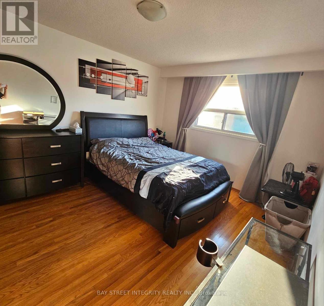 A bedroom with a large bed, wooden floors, and a mirror on the wall.
