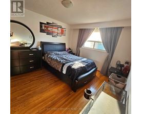A bedroom with a large bed, wooden floors, and a mirror on the wall.