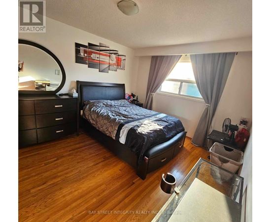 A bedroom with a large bed, wooden floors, and a mirror on the wall.
