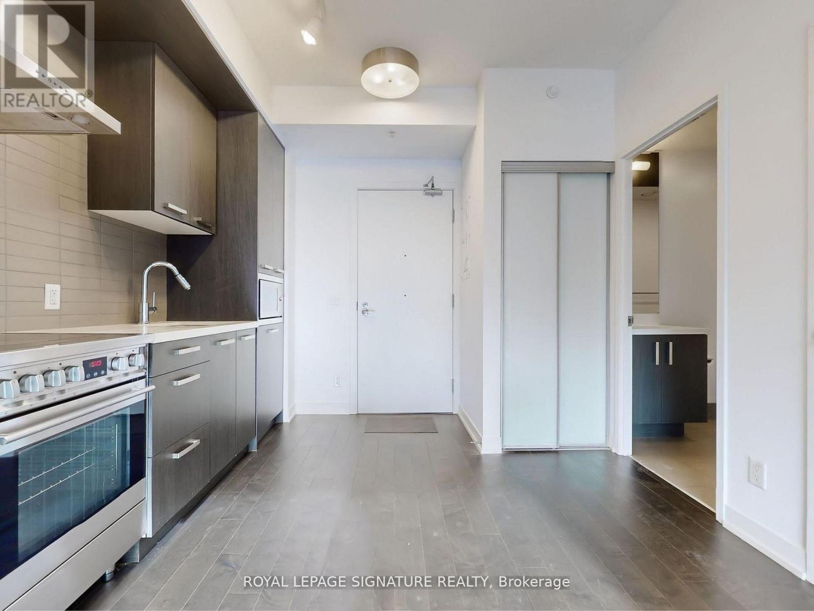 A modern kitchen with a stainless steel oven and a grey floor.