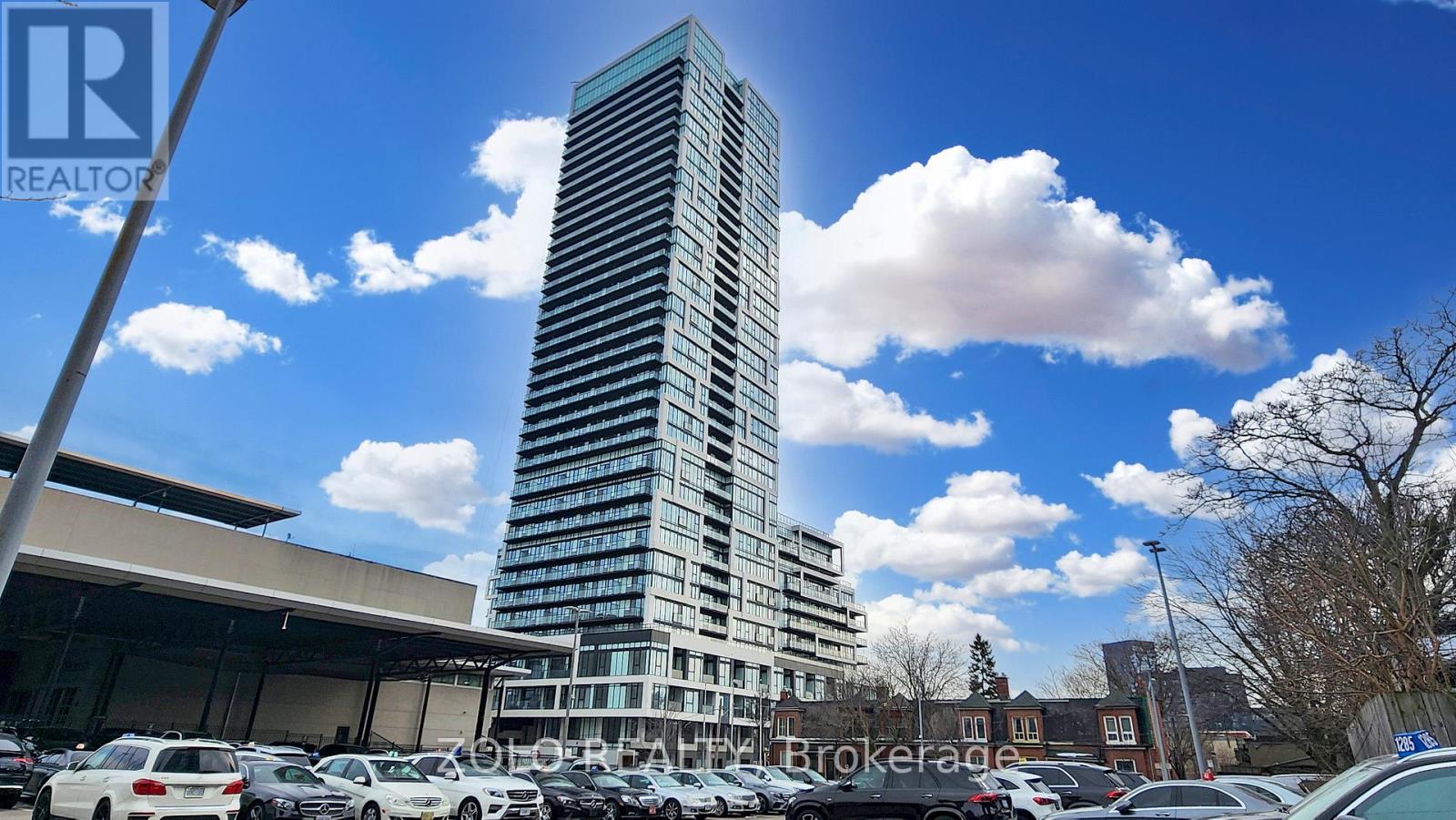 A tall building stands in a parking lot with a clear blue sky above.