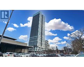 A tall building stands in a parking lot with a clear blue sky above.