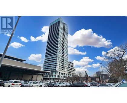 A tall building stands in a parking lot with a clear blue sky above.