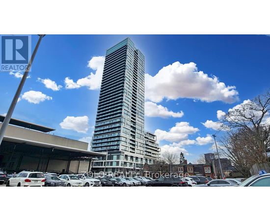 A tall building stands in a parking lot with a clear blue sky above.