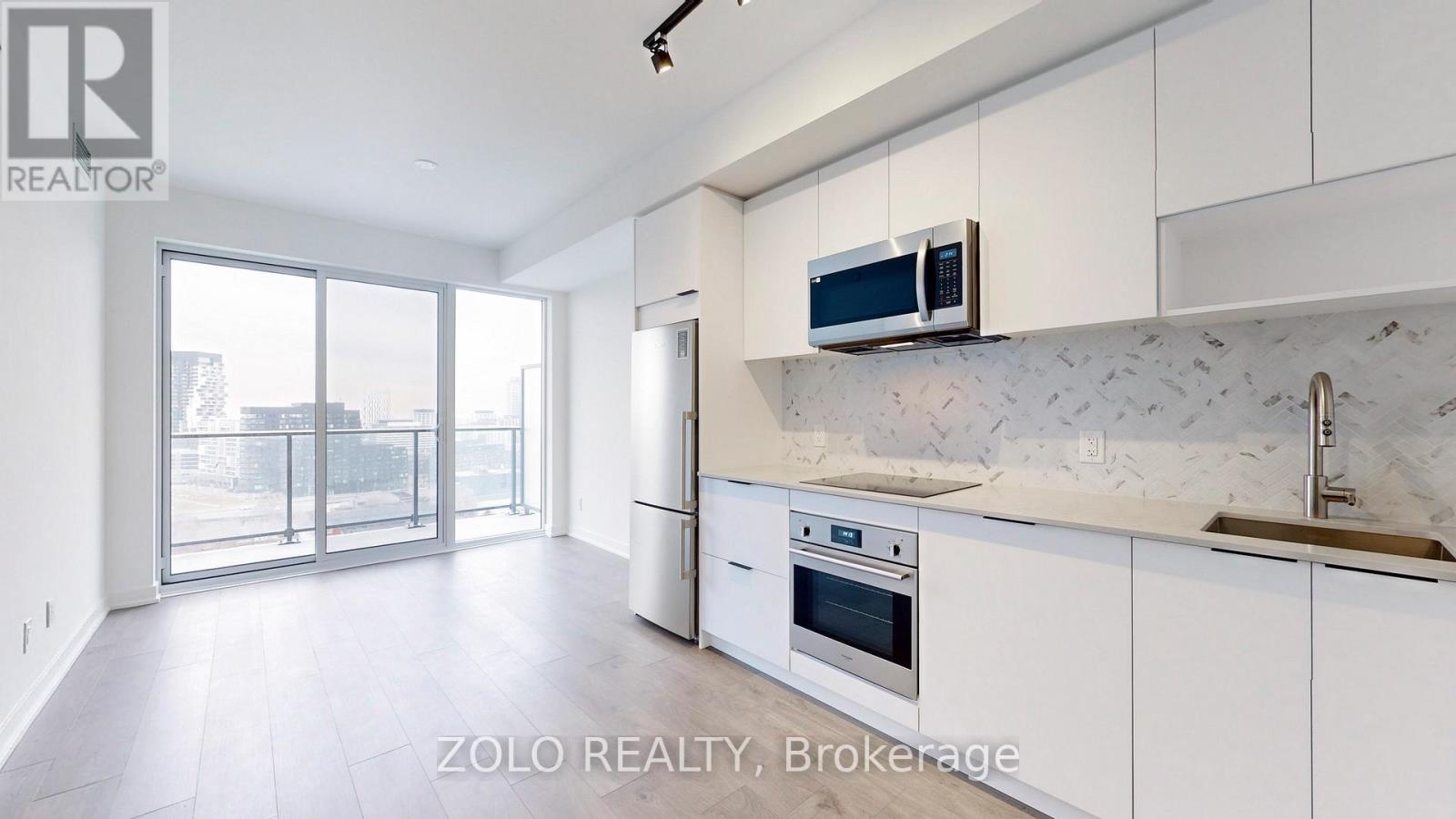 A modern kitchen with white cabinets and a marble backsplash.