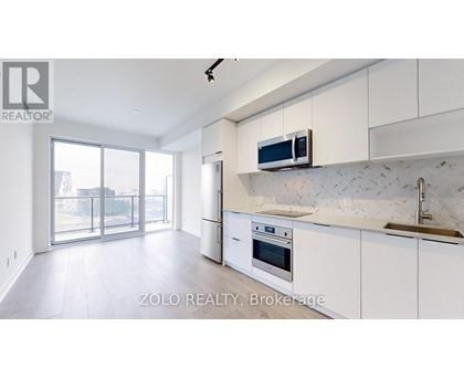A modern kitchen with white cabinets and a marble backsplash.