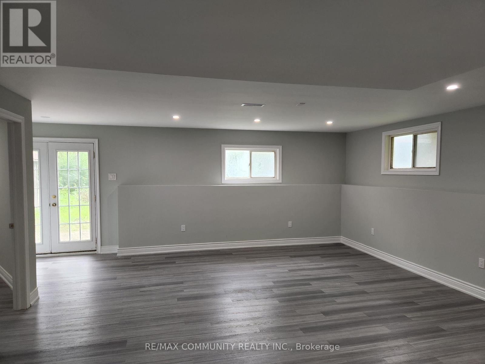 A spacious room with wooden flooring and white walls, ready for renovation.