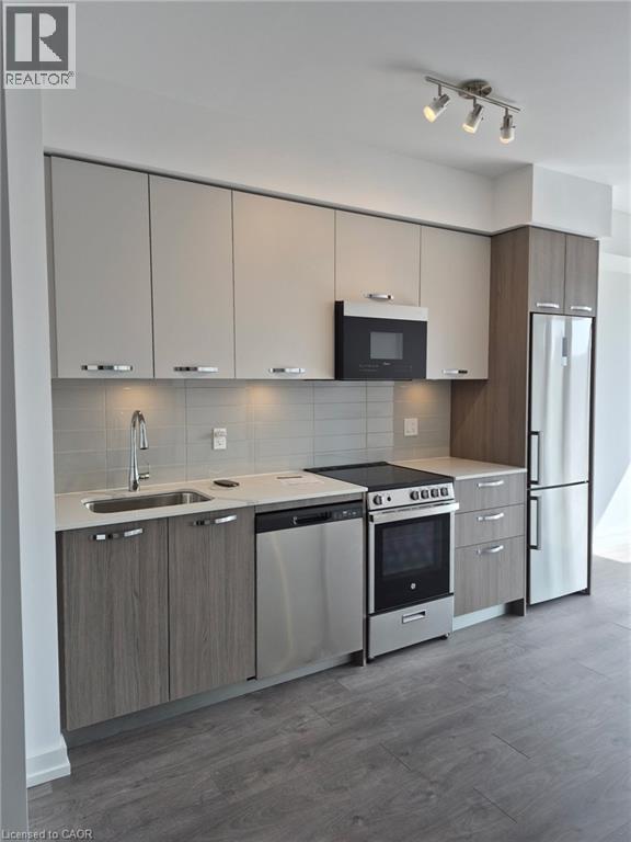 A modern kitchen with a refrigerator, sink, and cabinets.