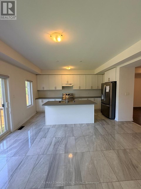 A spacious kitchen with a marble floor and a refrigerator on the right side.