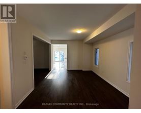 A spacious room with wooden floors and white walls.