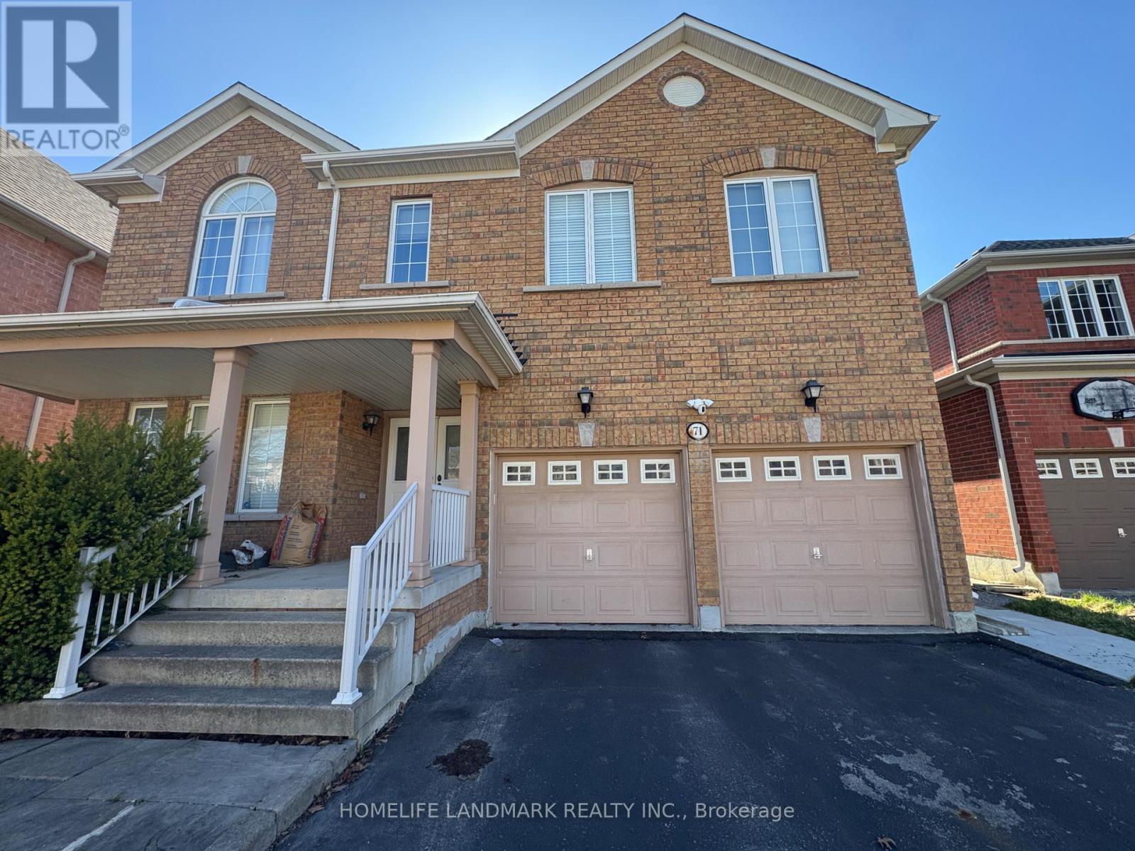 A brick house with a garage door is for sale.
