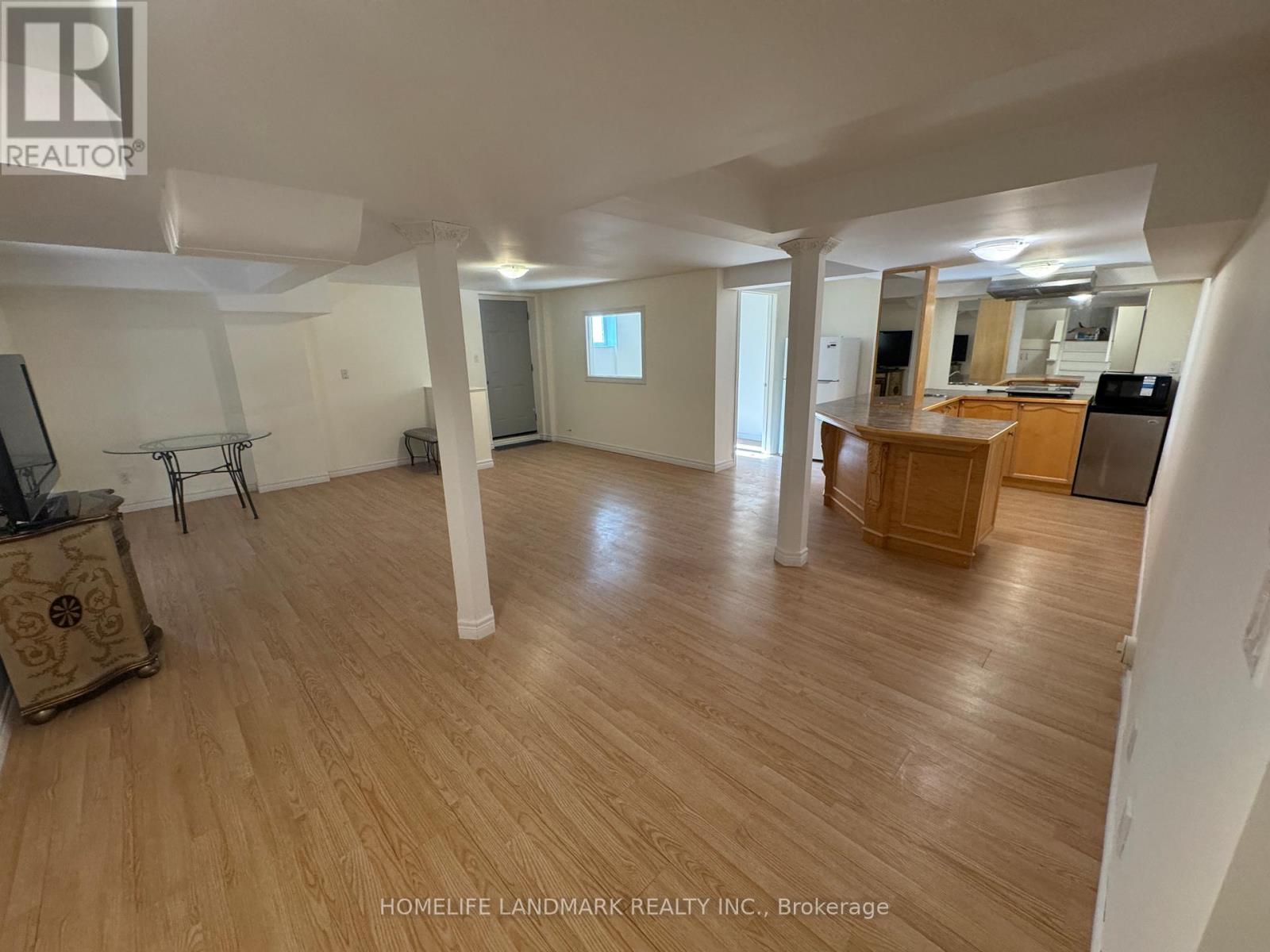 A spacious room with wooden flooring and white walls.
