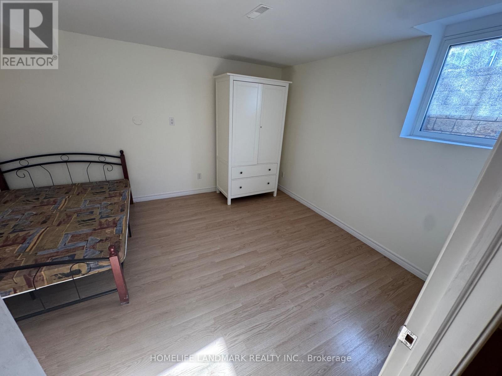 A bedroom with a bed, dresser, and window.