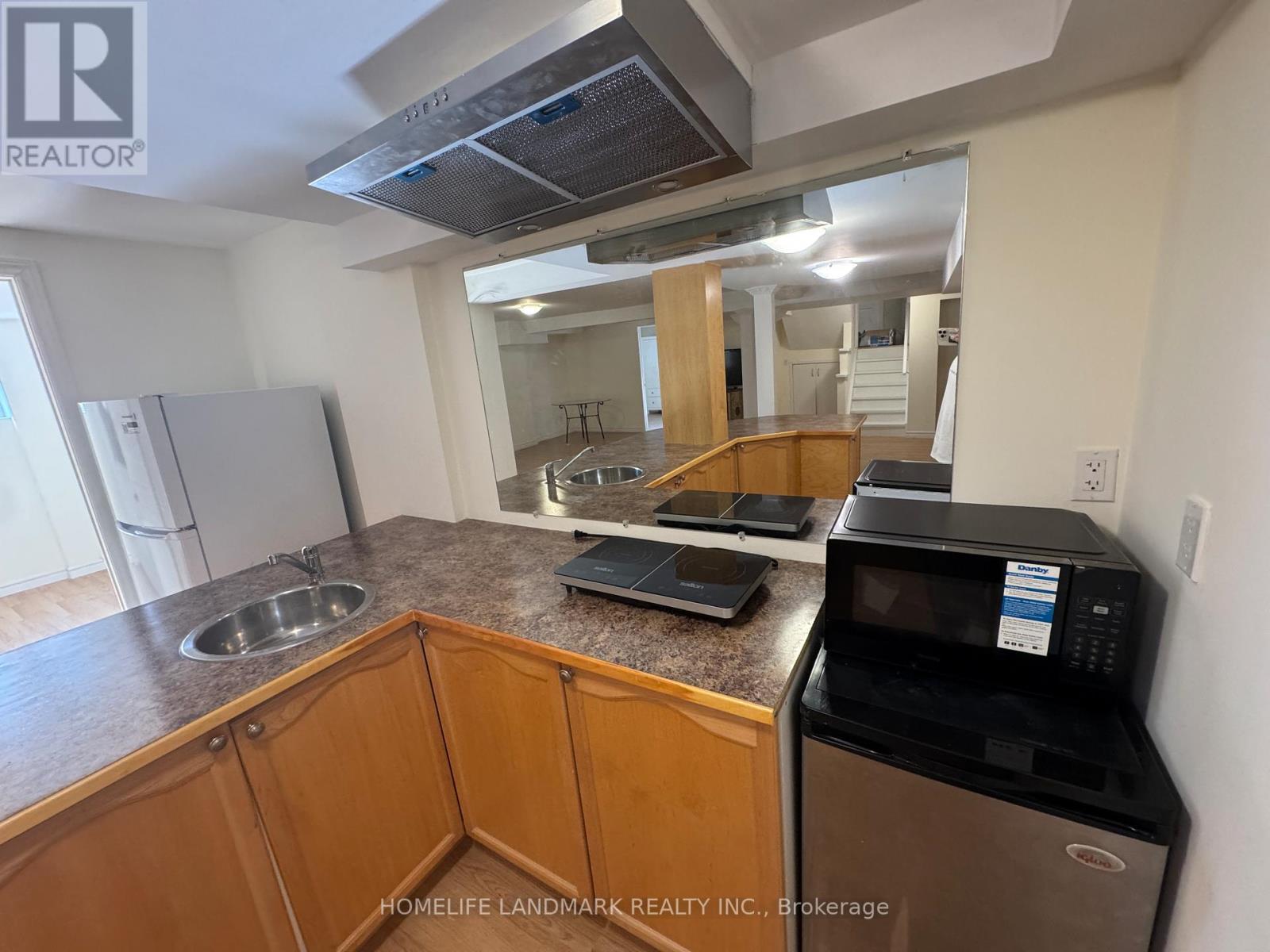 A kitchen with wooden cabinets and a black microwave.