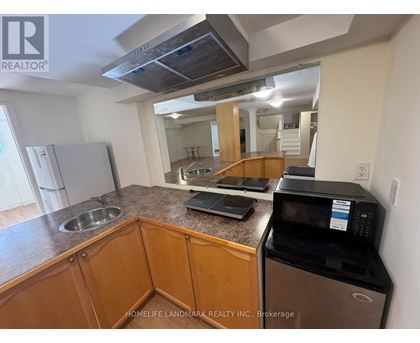 A kitchen with wooden cabinets and a black microwave.
