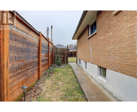 A wooden fence runs along the side of a brick house.