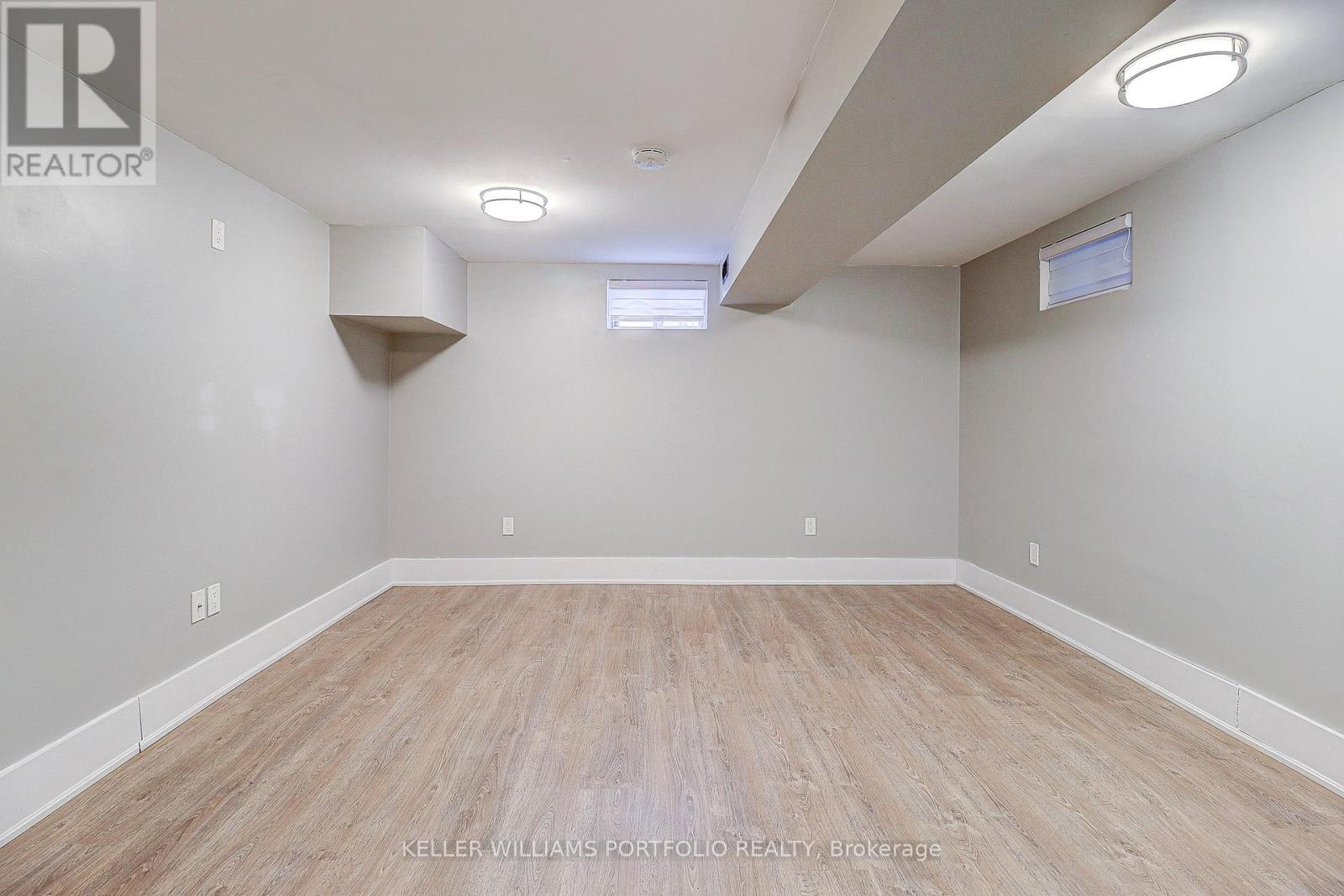 A spacious room with wooden flooring and white walls.