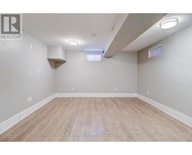 A spacious room with wooden flooring and white walls.