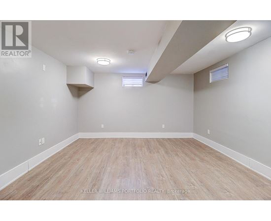A spacious room with wooden flooring and white walls.